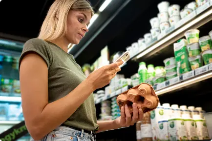 Shopper checking product information on her phone in a supermarket aisle